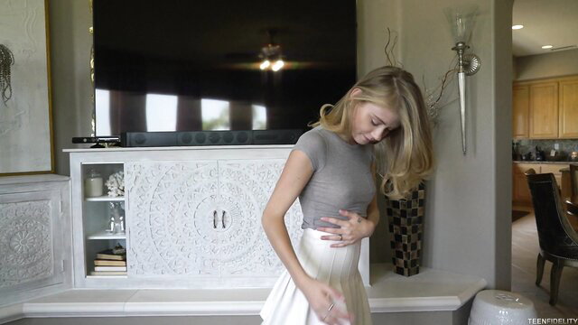 Hannah Hays in tight gray top and white skirt, hand on belly