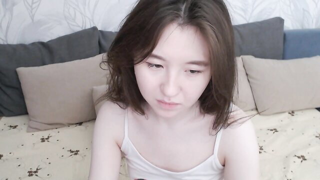 Cute Asian amateur teen in tank top on bed webcam closeup