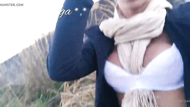 Busty blonde in open coat and white bra flashing cleavage outdoors