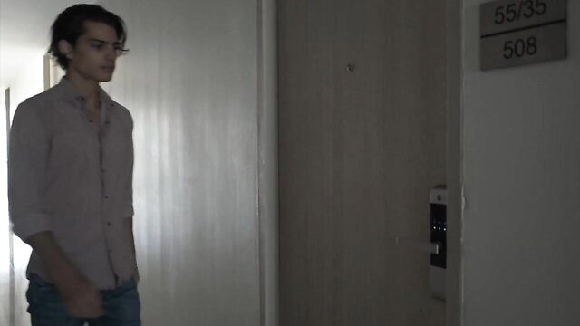 Handsome Asian guy in hallway outside hotel room door