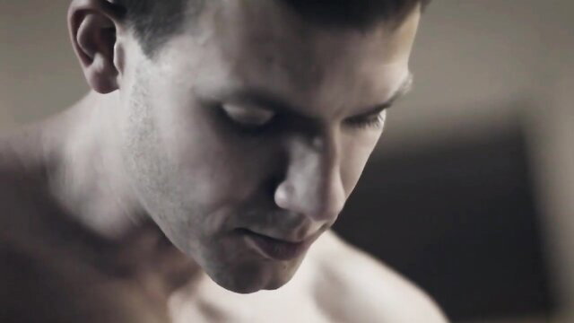 Handsome muscular white guy closeup portrait, bare chested in dim light