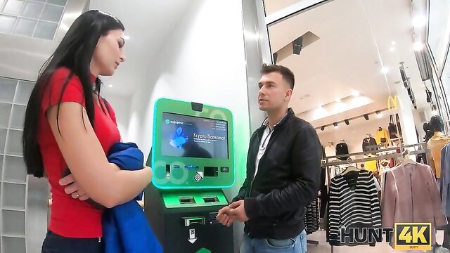 Brunette model in red top at green ATM with guy in mall