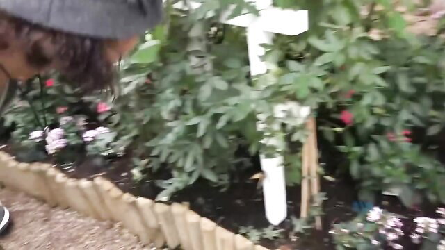 Holly Hendrix in garden hat kneels by cross-shaped plant stake