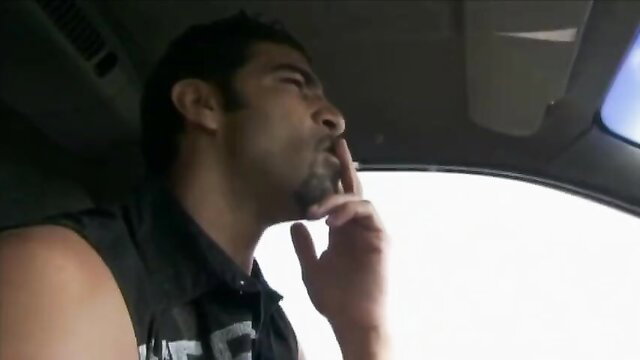 Handsome tanned man in car, thinking pose, big arms, tank top