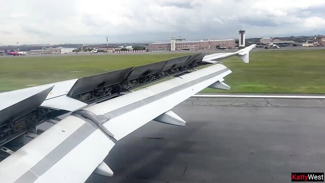 Airplane wing view from window during flight over airport runway