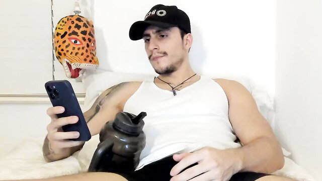 Spartacozz muscular Latino hunk in tank top, shorts, hat, chilling on bed