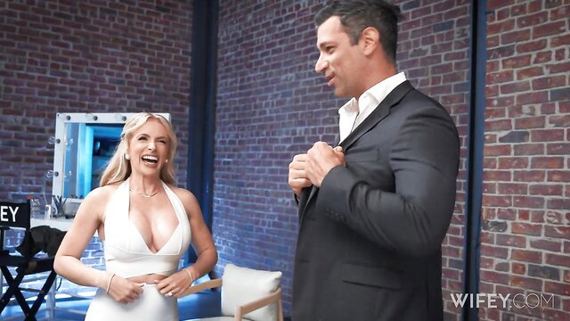 Danielle Renae in tight white dress smiles at suited man