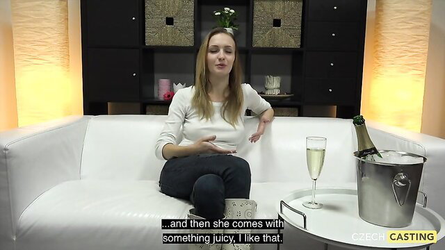 Belle Claire sips champagne in white top and jeans on couch