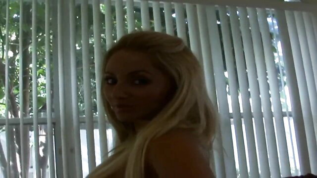 Blonde Eva Cruz topless profile by window in lesbian tease