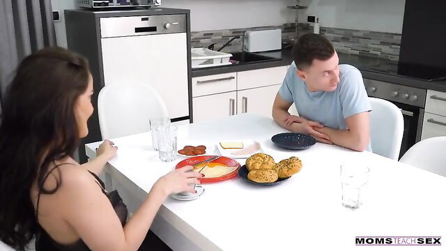 Brunette stepmom in low-cut dress teases at kitchen table with guy