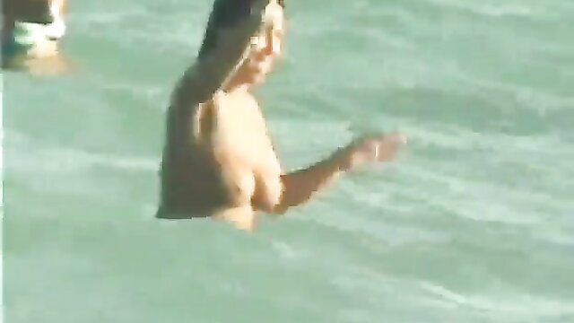 Nude teen girl with big tits splashing in turquoise beach water