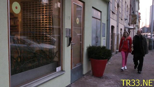 Blonde cutie in pink pants and red coat walks with man outside store