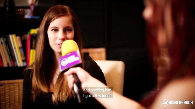 Vanda Angel holds yellow mic in tight black top, wild fetish tease