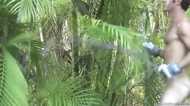 Muscular shirtless man in jungle with machete, furry palms backdrop