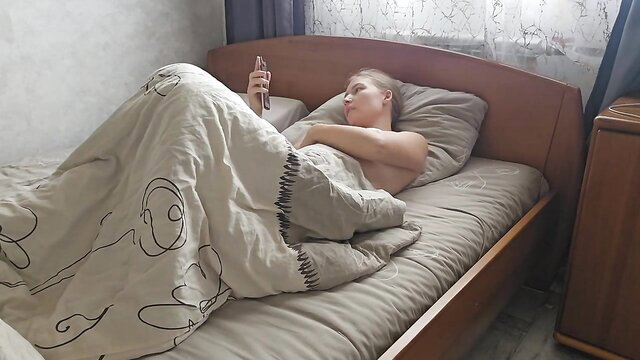 Blonde amateur babe masturbates nude in bed watching porn on phone