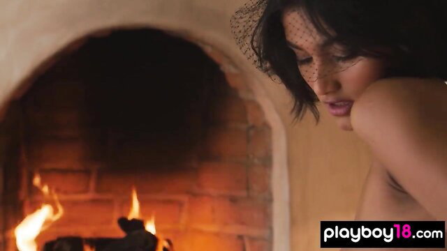 Petite Asian muse nude by fireplace, seductive gaze