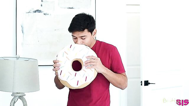 Asian guy hugging giant plush donut toy, teasing adult fun