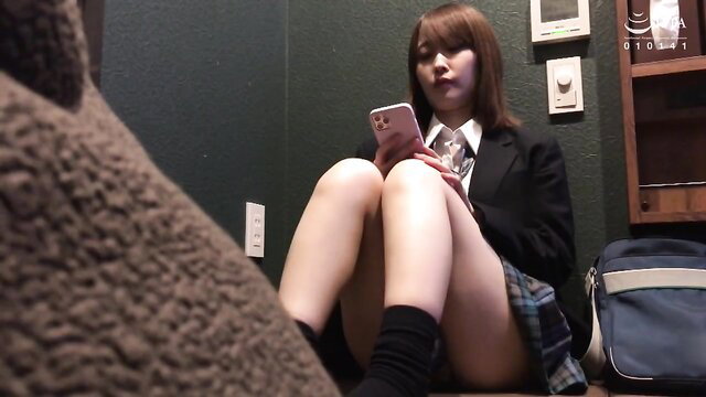 Japanese schoolgirl in skirt and stockings sits legs open checking phone