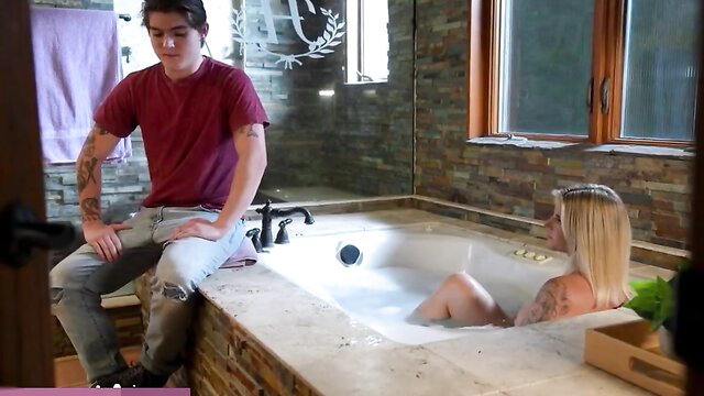 Tattooed guy watches busty blonde stepmom naked in tub, tits out