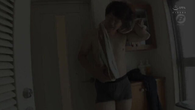 Asian guy in white shirt and shorts dressing by window in JAV scene