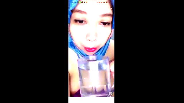 Asian hijab girl in blue headscarf drinks water, cleavage tease closeup