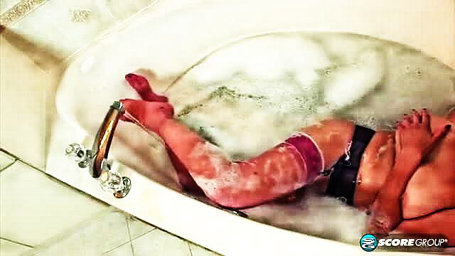 Busty babe in stockings bathes with man, soapy legs tease in tub