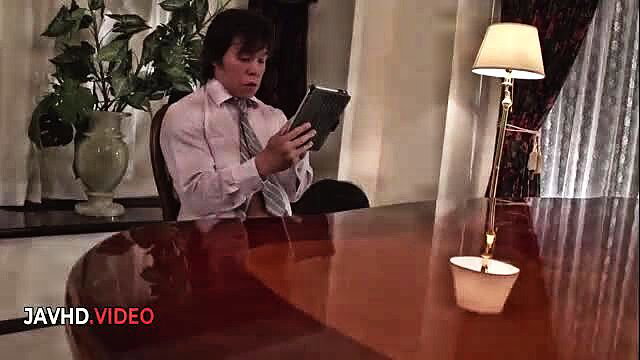 Japanese man in suit reading tablet at desk in JAV scene