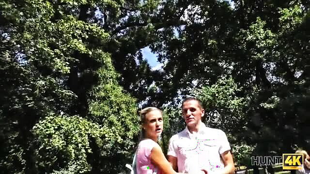 Blonde girlfriend in pink top with man in park, cuckold watches