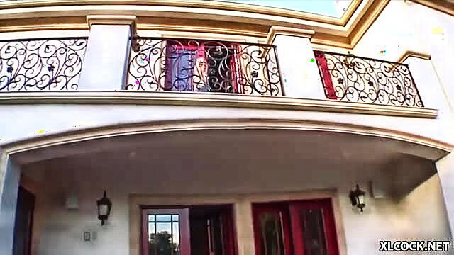 Yasmine Gold at luxurious balcony door with Rico Strong, teasing view