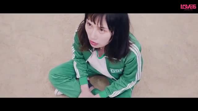Asian woman in tight green tracksuit squats with glossy lips, Squirt Game Ep 2