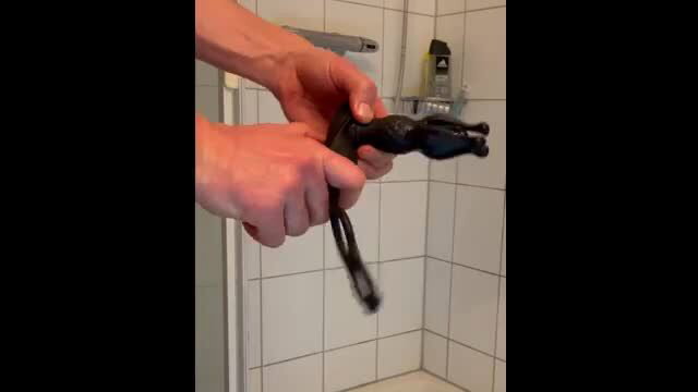 Man testing extreme electro anal plug in shower closeup