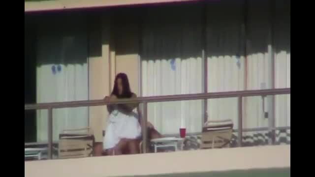 Hot brunette amateur babe in mini skirt leans on balcony railing