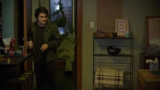 Curly-haired Latino guy in leather jacket standing by bar in sexy scene