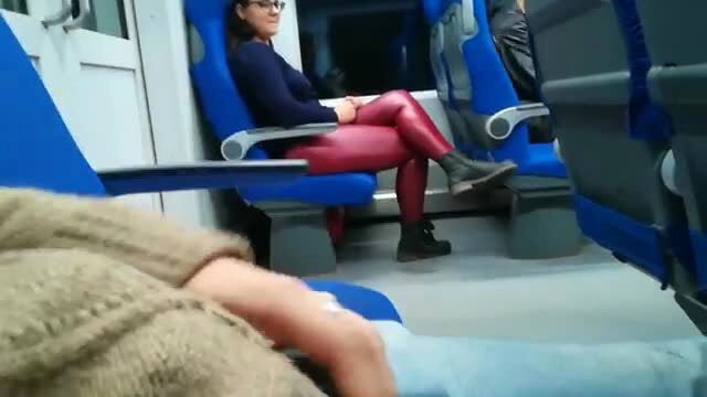 Brunette in tight red leggings sits legs crossed on train seat
