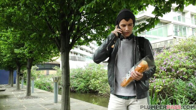 Skinny emo twink in hoodie calls on phone holding baguette outdoors