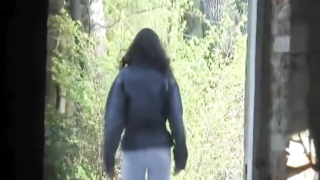 Black woman in tight pants and jacket walks into woods to pee urgently