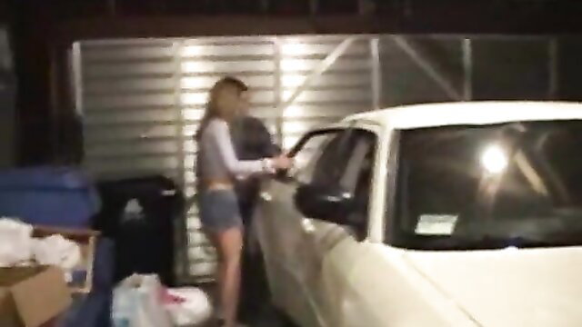Hot blonde college girl in shorts bending over car door in garage