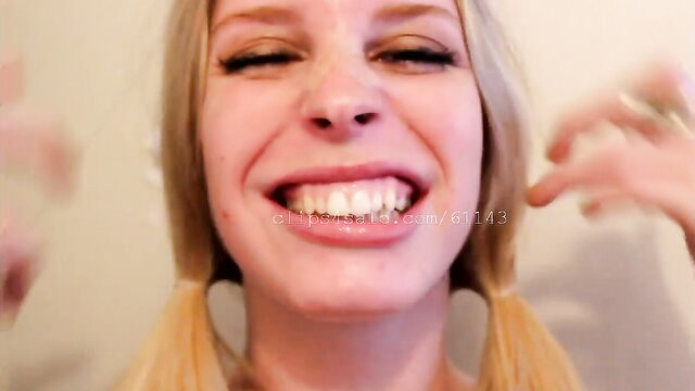 Blonde babe with pigtails smiles wide, teasing tongue mouth fetish closeup