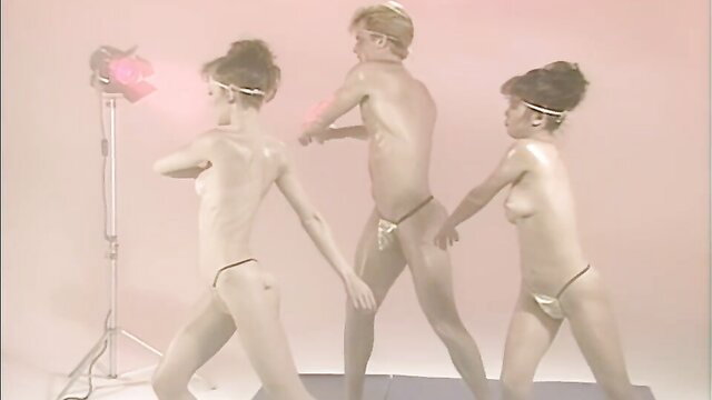 John Holmes nude with two topless Asian women in pink thong dance