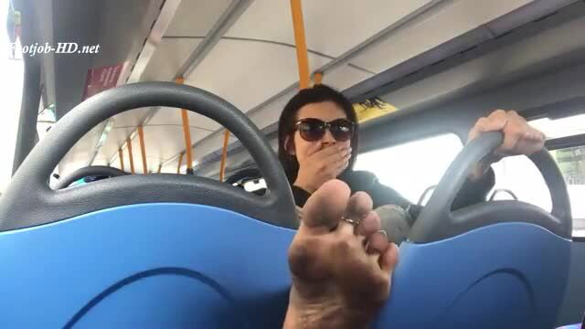 Asian bus driver shows dirty bare feet, sunglasses on