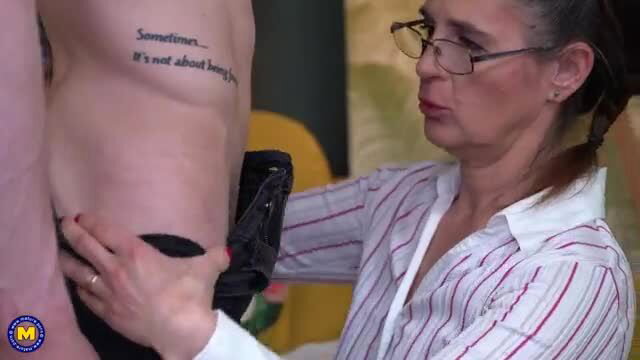 Brunette mature with glasses kneels sucking tattooed man's hard cock