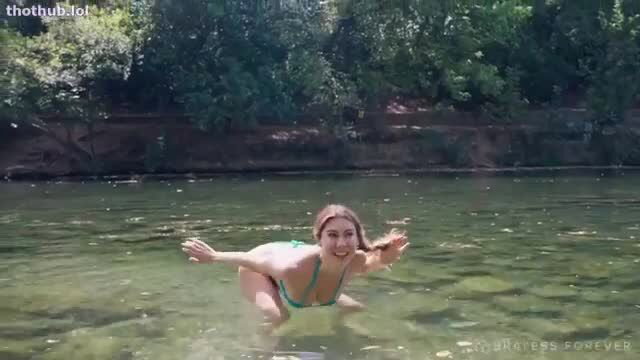 Emma James in emerald bikini splashing in green river, wet teasing pose