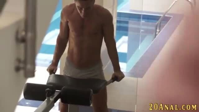 Muscular man in gray briefs gripping gym bench by pool