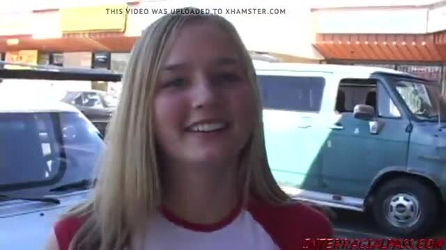 Blonde teen smiling outdoors by green van in parking lot