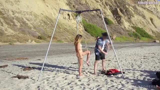 Blonde Emma nude suspended in Shibari frame on beach with Nikki