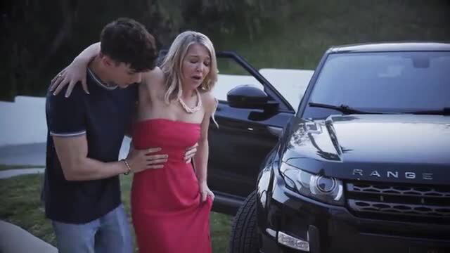 Laura Bentley in tight red dress hugged by guy near Range Rover