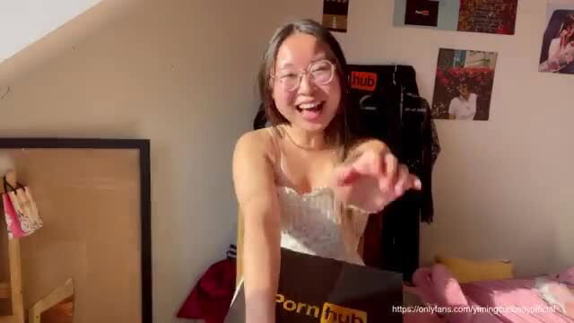 Smiling thick Asian cutie in lace top holds Pornhub box, happy face