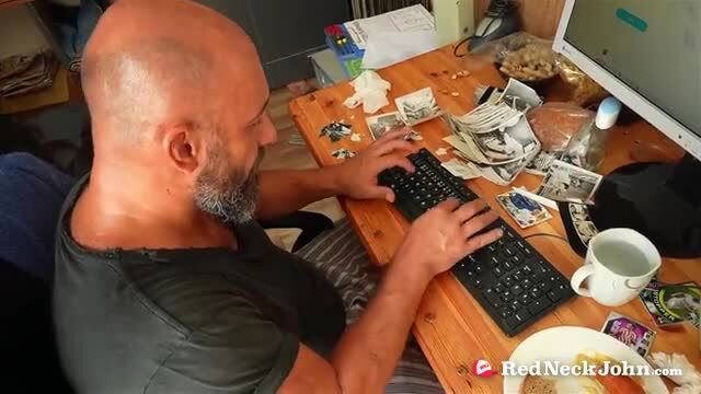 Bald bearded Redneck John at cluttered desk with cash and photos