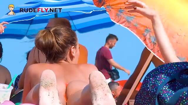 Nudist teen's sandy bare ass on beach lounger, topless tease