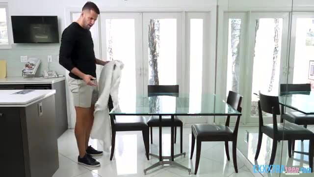 Dan Damage in shorts holding sheet in kitchen scene